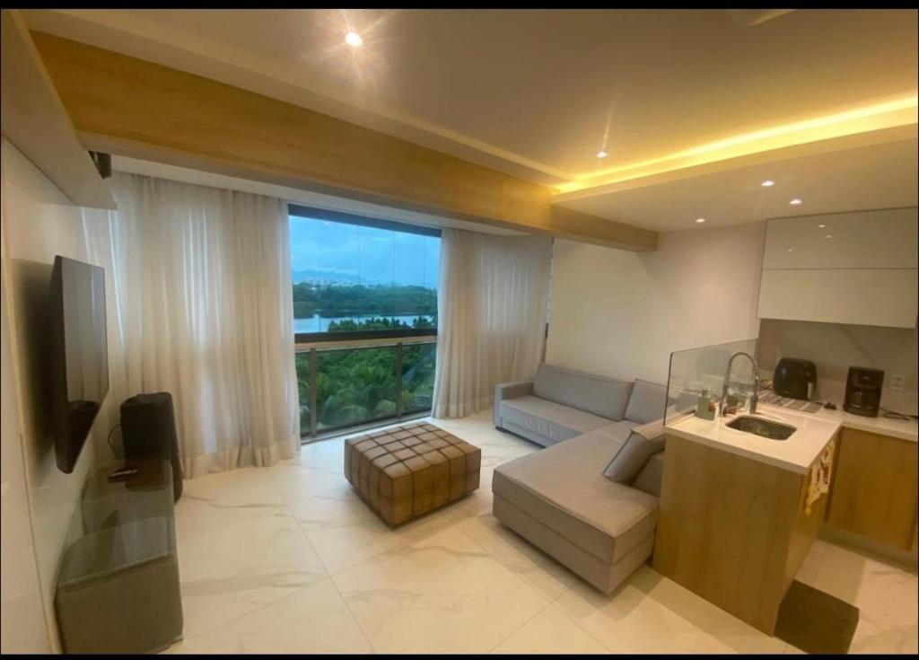 a living room with a couch and a large window at Apto de frente para a praia com vista pra lagoa in Rio de Janeiro