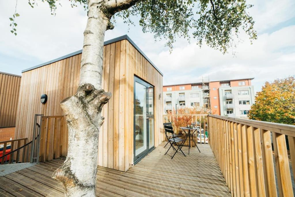 a wooden deck with a tree next to a building at Delores Eco-Pod / Treehouse, Walk to Cabot Circus in Bristol