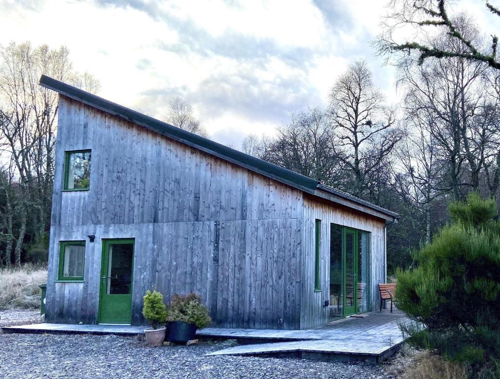 a barn with green doors on a gravel yard at Betula Chalet – coast & country in the Highlands in Nairn