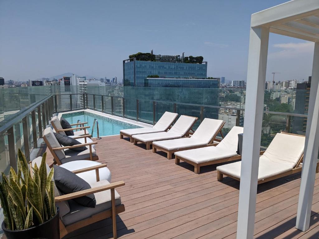 eine Terrasse mit Liegestühlen und einen Pool auf einem Gebäude in der Unterkunft Encantador apartamento en Miraflores in Lima