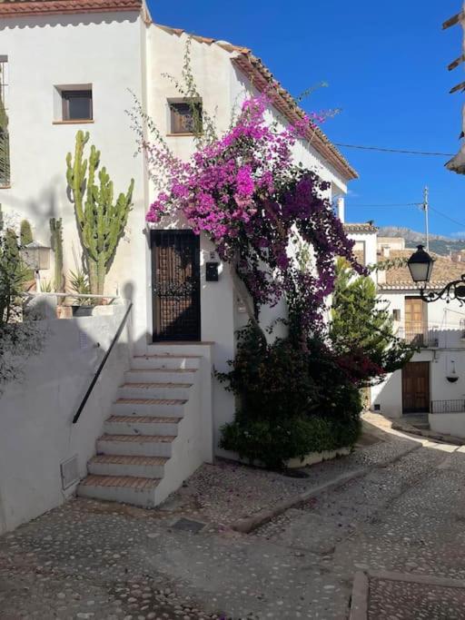 a white house with a door with purple flowers at Classical corner town house in historical centre in Altea