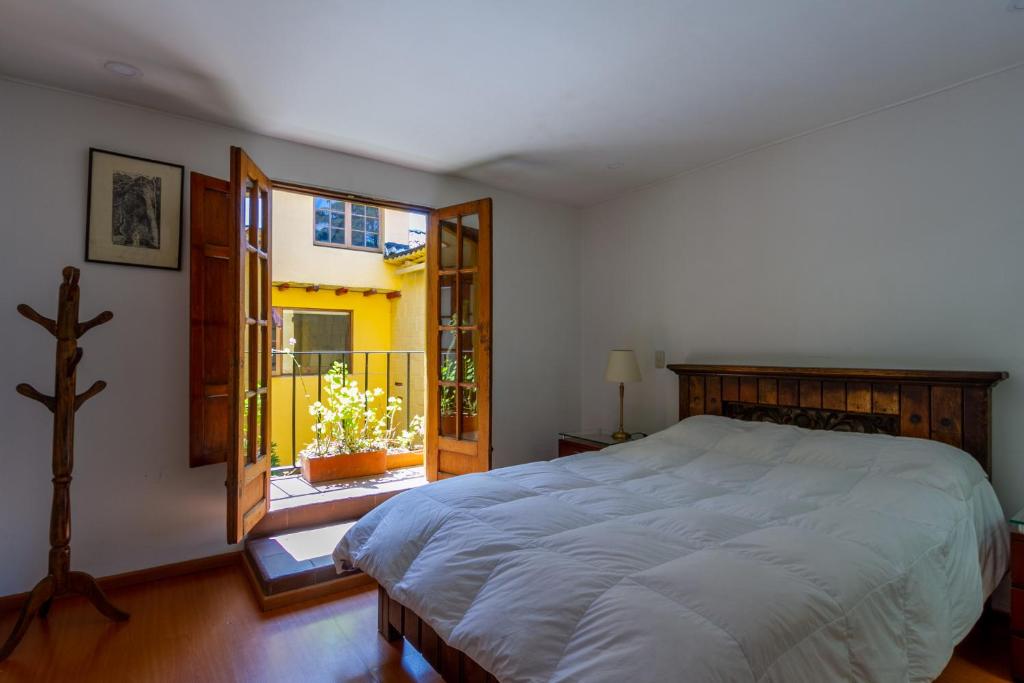 Un dormitorio con una cama grande y un balcón. en Apartaestudios La Candelaria, en Bogotá