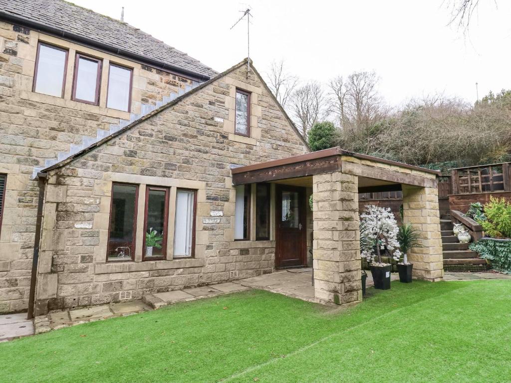 a stone house with a grass yard in front of it at Moor Cottage in Oldham