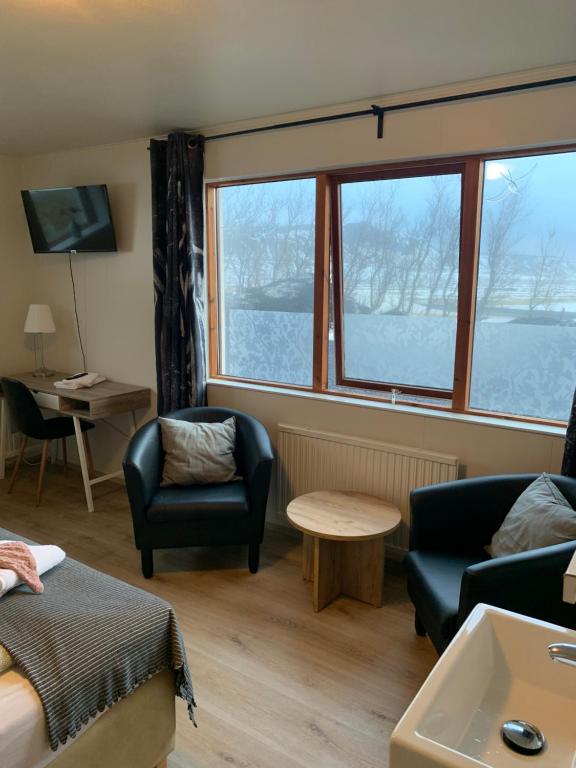 uma sala de estar com 2 cadeiras, uma mesa e janelas em Skammidalur Guesthouse em Vík