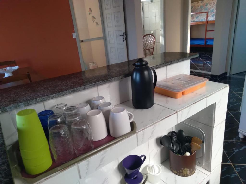 eine Küchentheke mit Flaschen und Tassen darauf in der Unterkunft Casa Arejada, bem localizada para Temporada em Caraguatatuba in Caraguatatuba