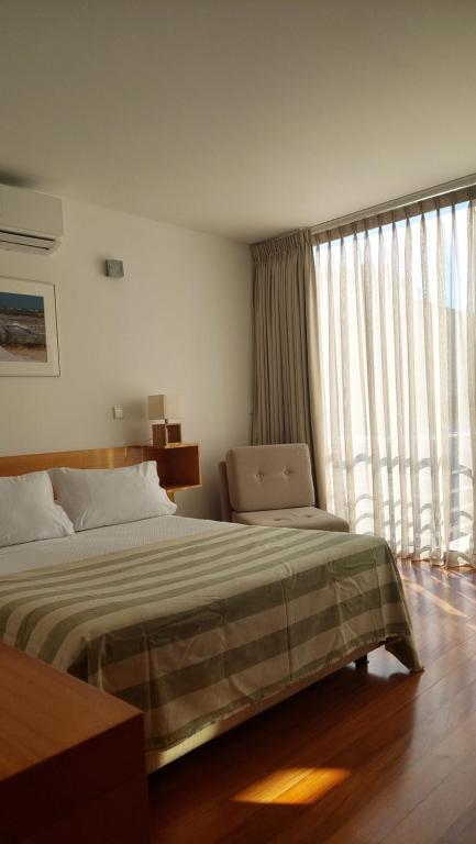 a bedroom with a bed and a large window at Varandas da Ria in Costa Nova