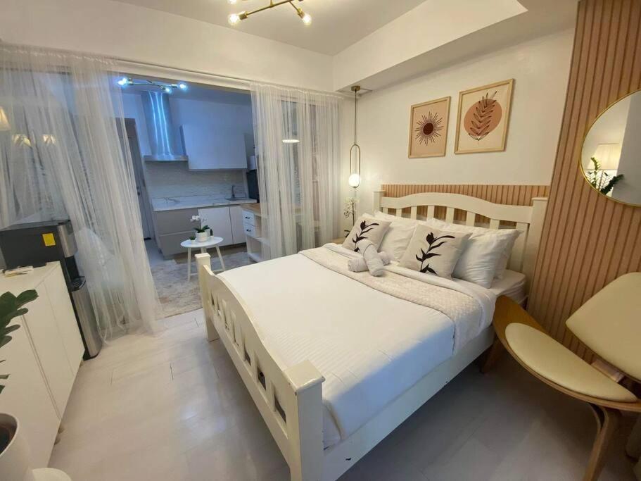 a bedroom with a large white bed and a table at Azure BEACHfront view Aesthetic Minimalist unit in Manila