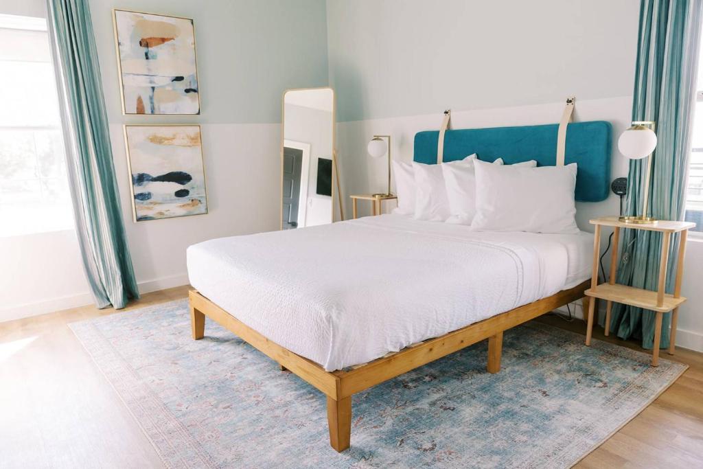 a bedroom with a large white bed with a blue headboard at Unit 213 - The Strand 2 Bed - Cation on the Guadalupe in New Braunfels