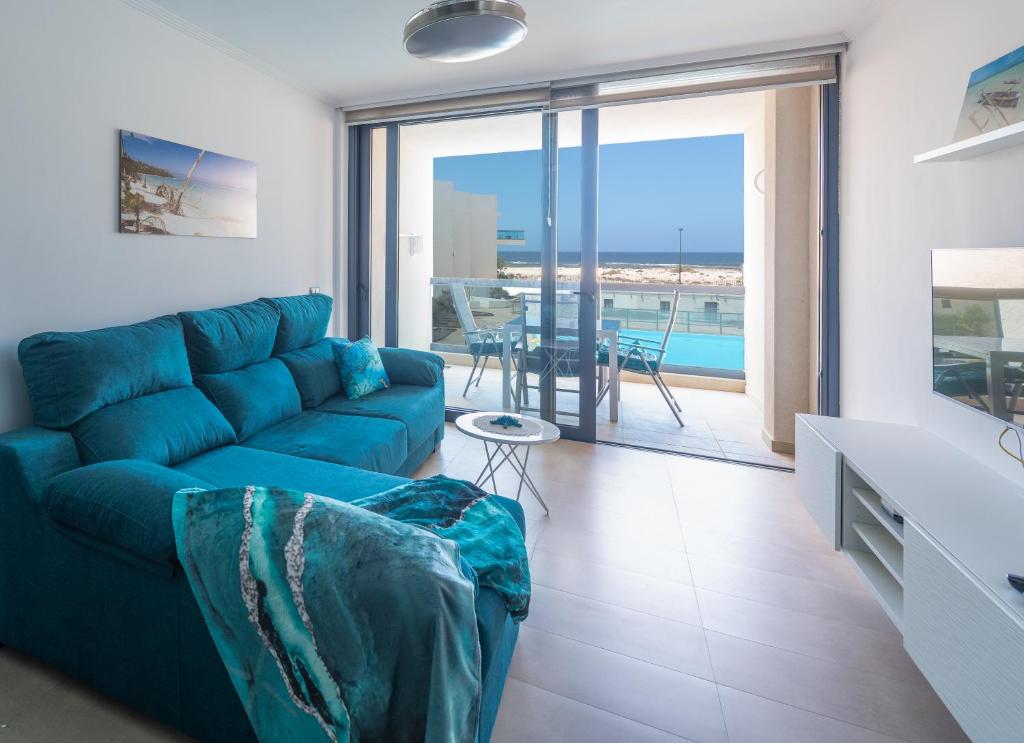 a living room with a blue couch and a view of the ocean at Calypso in Cotillo