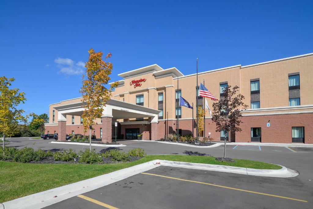 un immeuble de bureaux doté d'un drapeau américain devant lui dans l'établissement Hampton Inn Brighton Mi, à Brighton