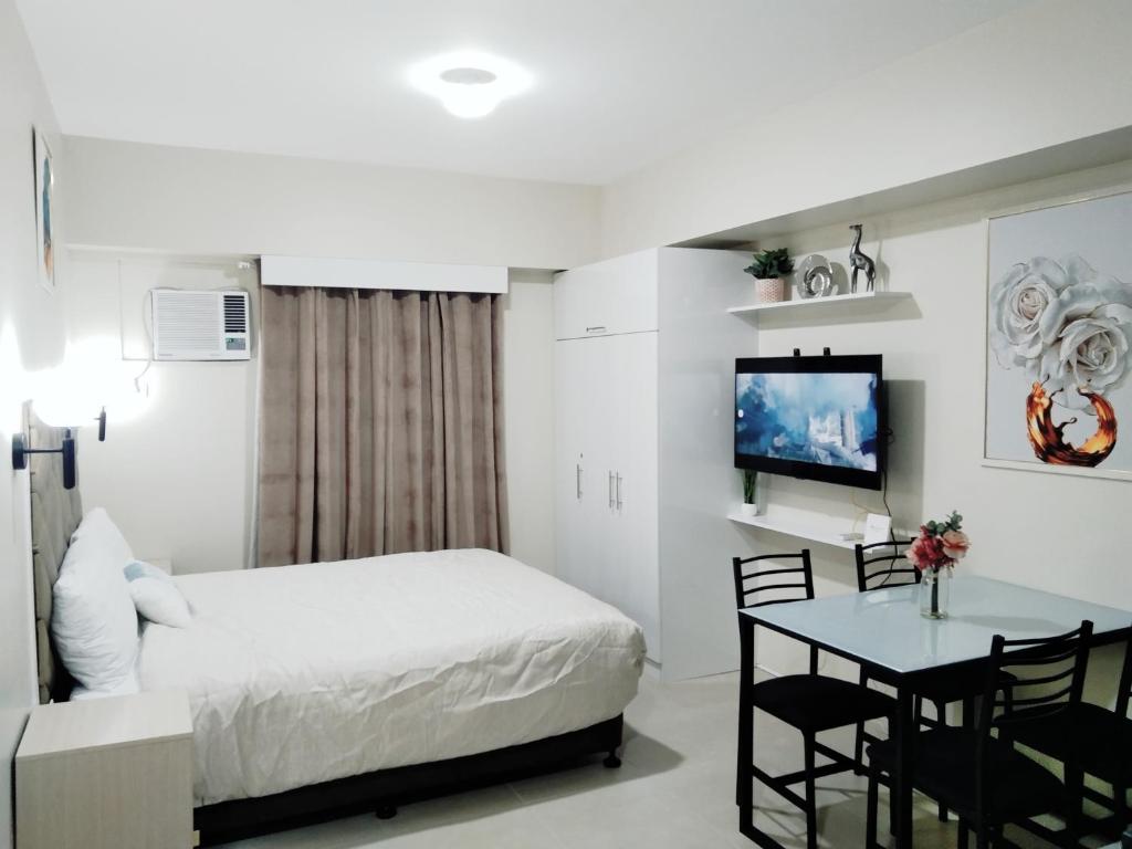 een slaapkamer met een bed, een tafel en een televisie bij Avida Towers Riala T3 - Studio Unit 2nd Floor - 224 in Cebu City