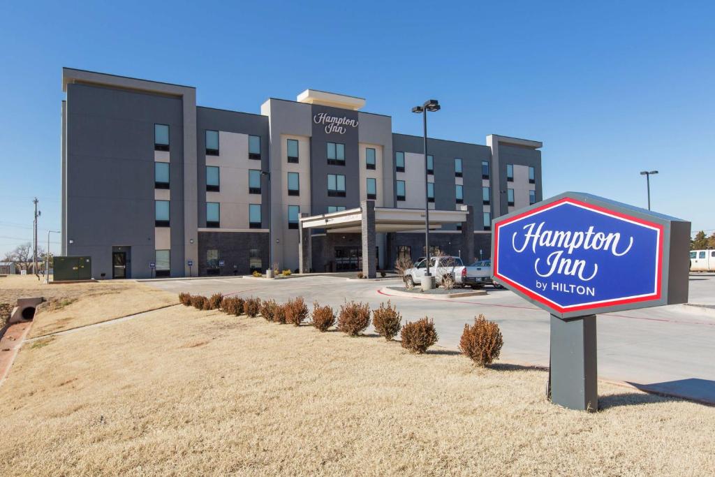 a sign in front of a large building at Hampton Inn Mustang in Mustang