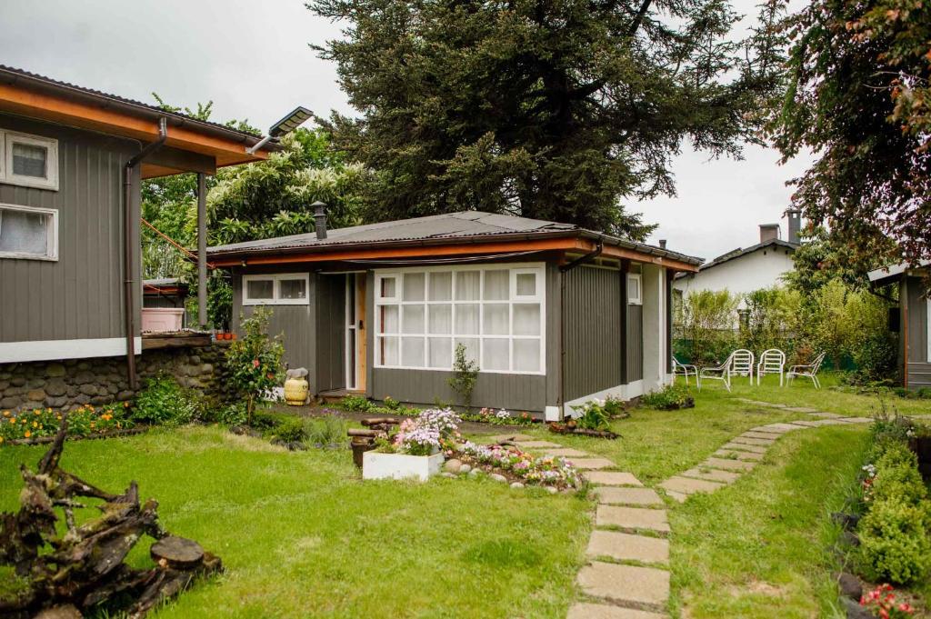 un patio trasero con una casa y un patio con césped sidx sidx sidx sidx en Leftraro Lodge Urbano, en Villarrica