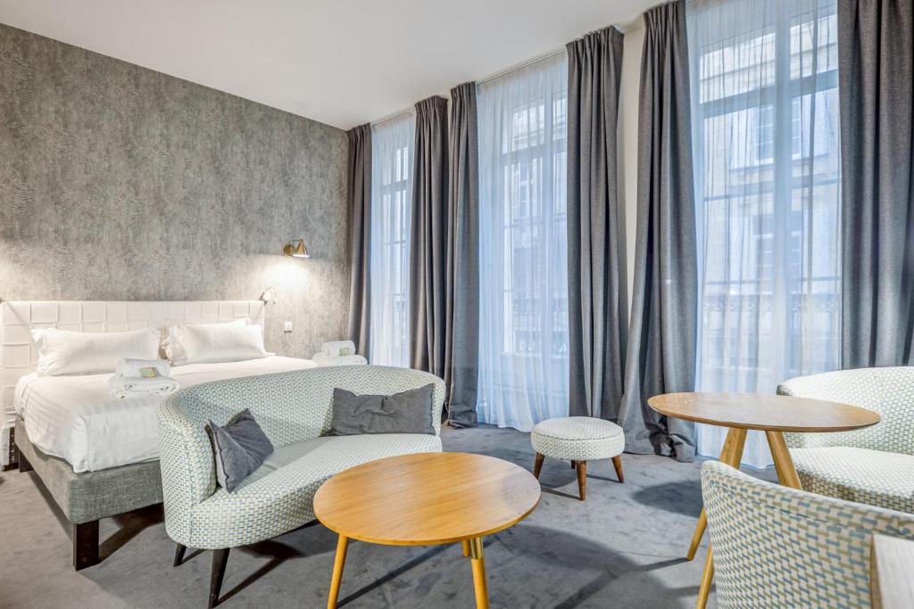 um quarto de hotel com uma cama, cadeiras e janelas em Vallier Suite n18 - Exceptional suite in Bordeaux - Welkeys em Bordéus