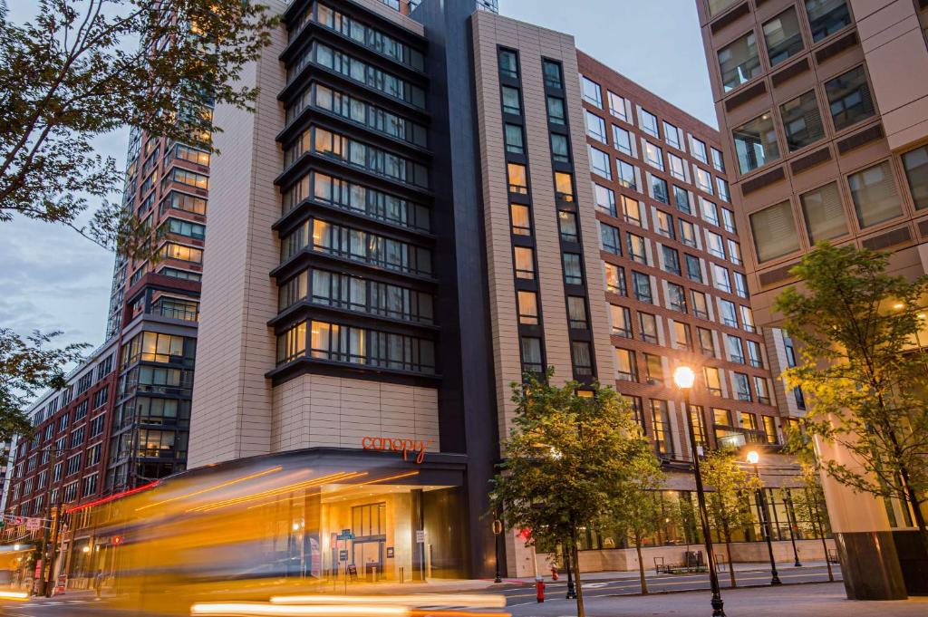 a bus driving in front of a tall building at Canopy By Hilton Jersey City Arts District in Jersey City