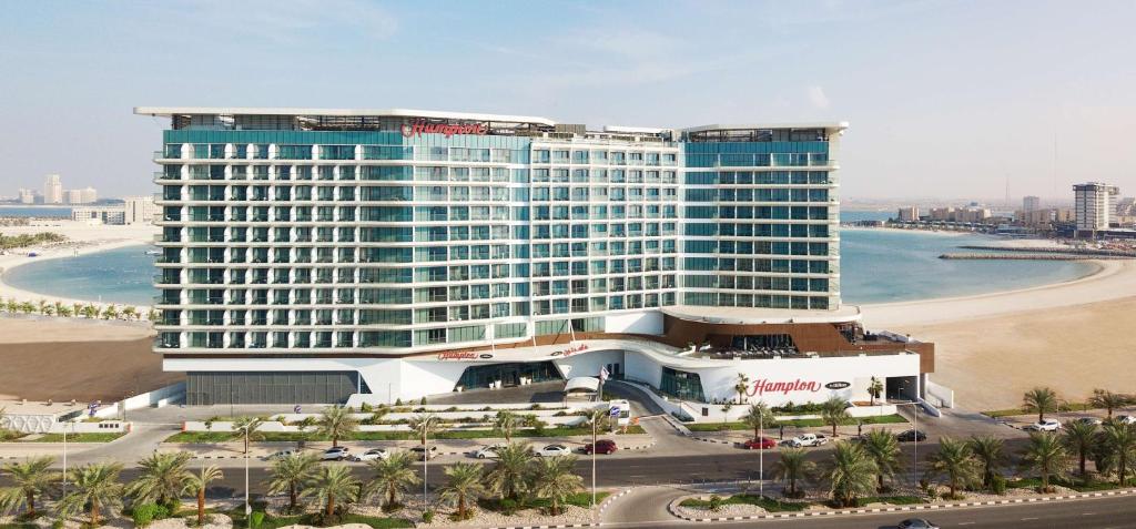 a large building on the beach next to the ocean at Hampton by Hilton Marjan Island in Ras al Khaimah