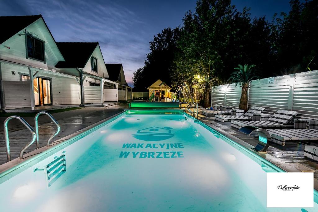 a swimming pool with lounge chairs in a backyard at night at Domki Wakacyjne Wybrzeże in Mielno