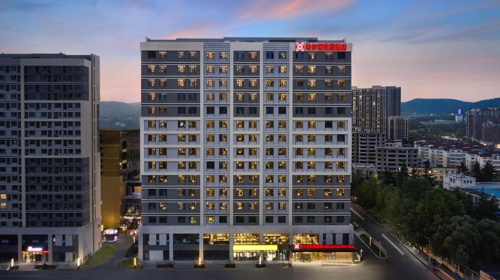 a tall building with lights on in a city at Hilton Garden Inn Jincheng Gushuyuan in Jingcheng