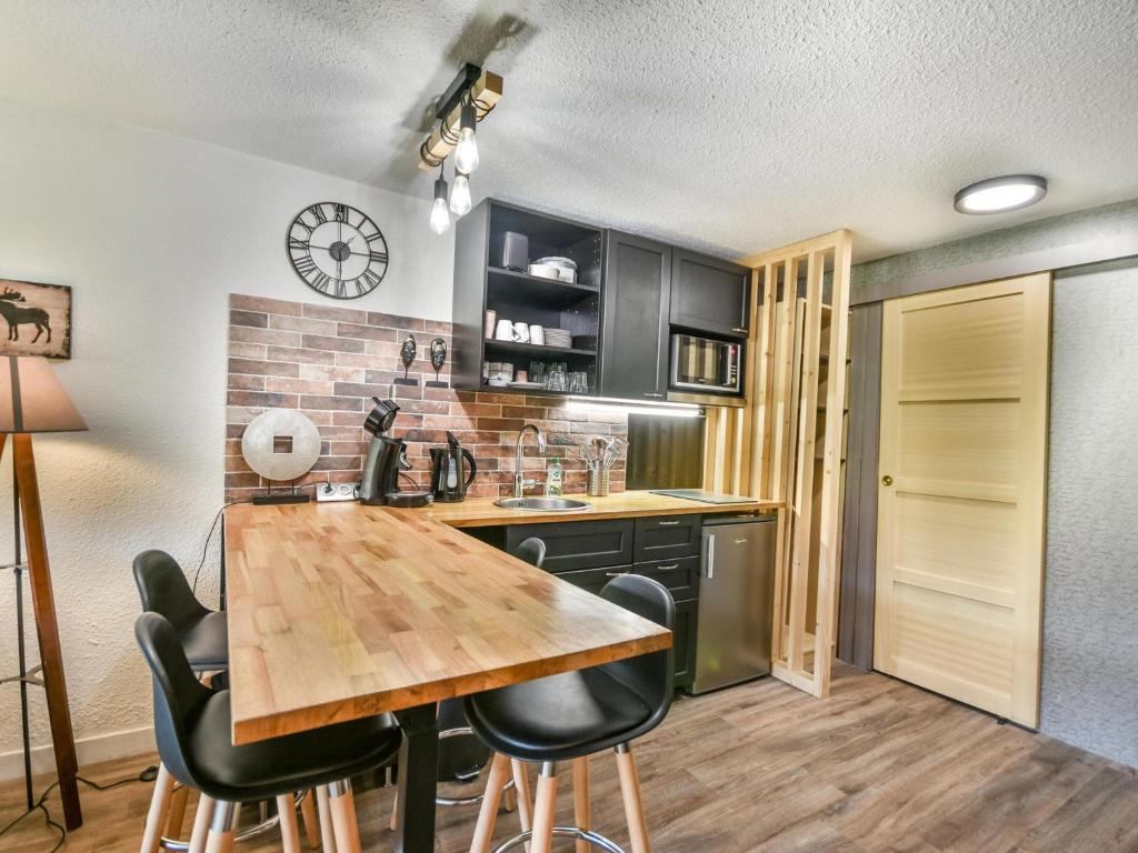 une cuisine avec une table en bois et des armoires noires dans l'établissement Studio Cabine Rénové au Centre des Gets, Proche Remontées Mécaniques - FR-1-685-34, aux Gets