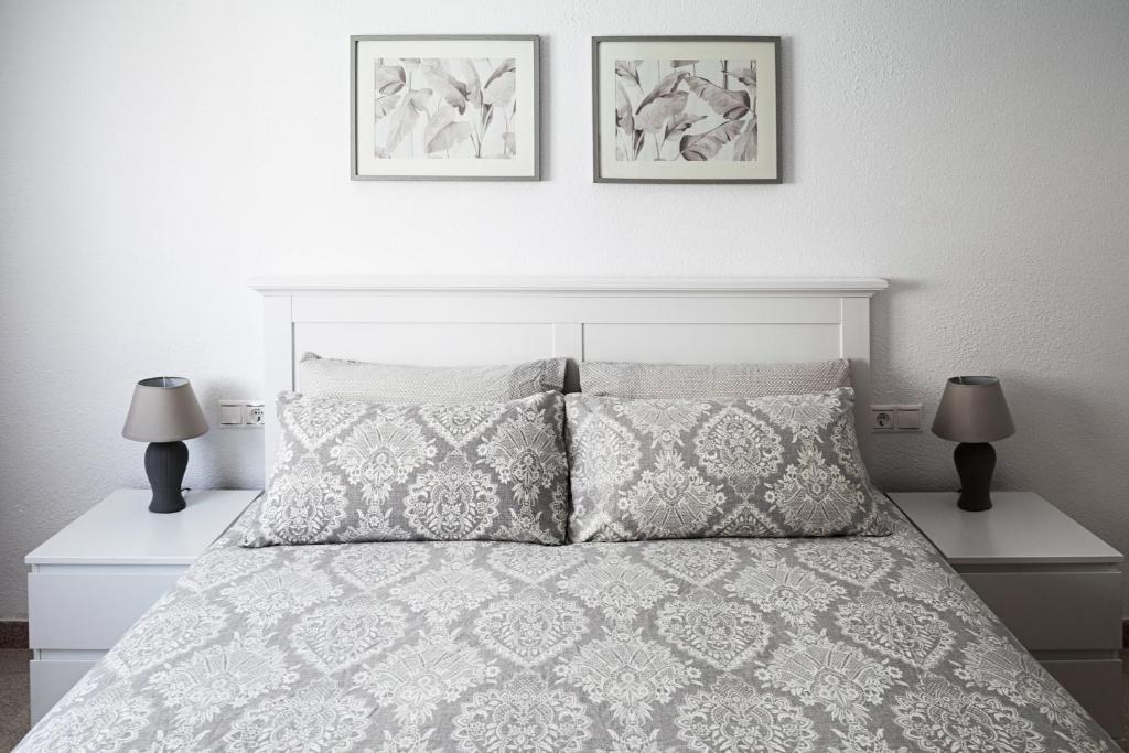 a bedroom with a white bed with two lamps at Hola Mar in Torrevieja