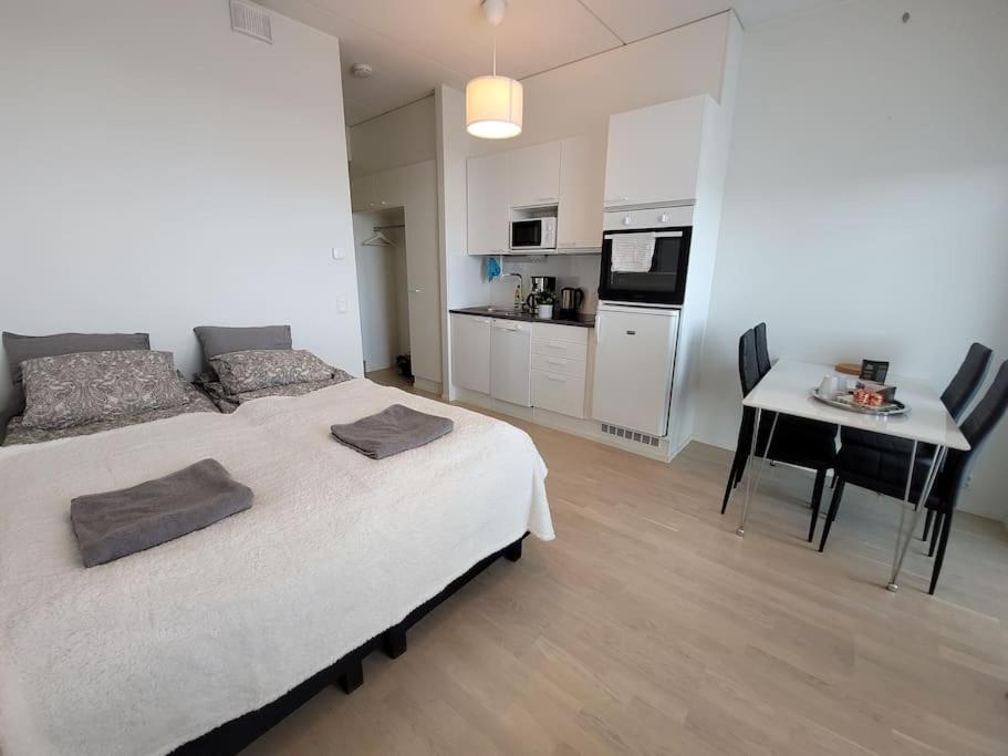 a bedroom with a bed and a table and a kitchen at Bright studio apartment on the 6th floor in Kerava