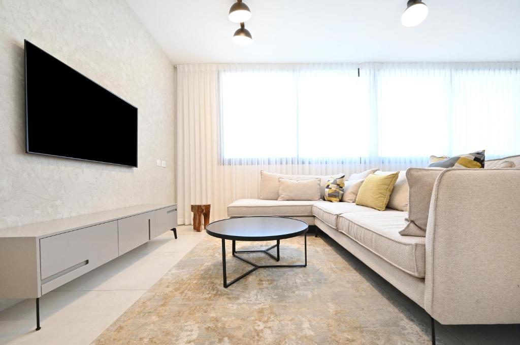 een woonkamer met een bank en een tv bij Summer White by HolyGuest in Tel Aviv