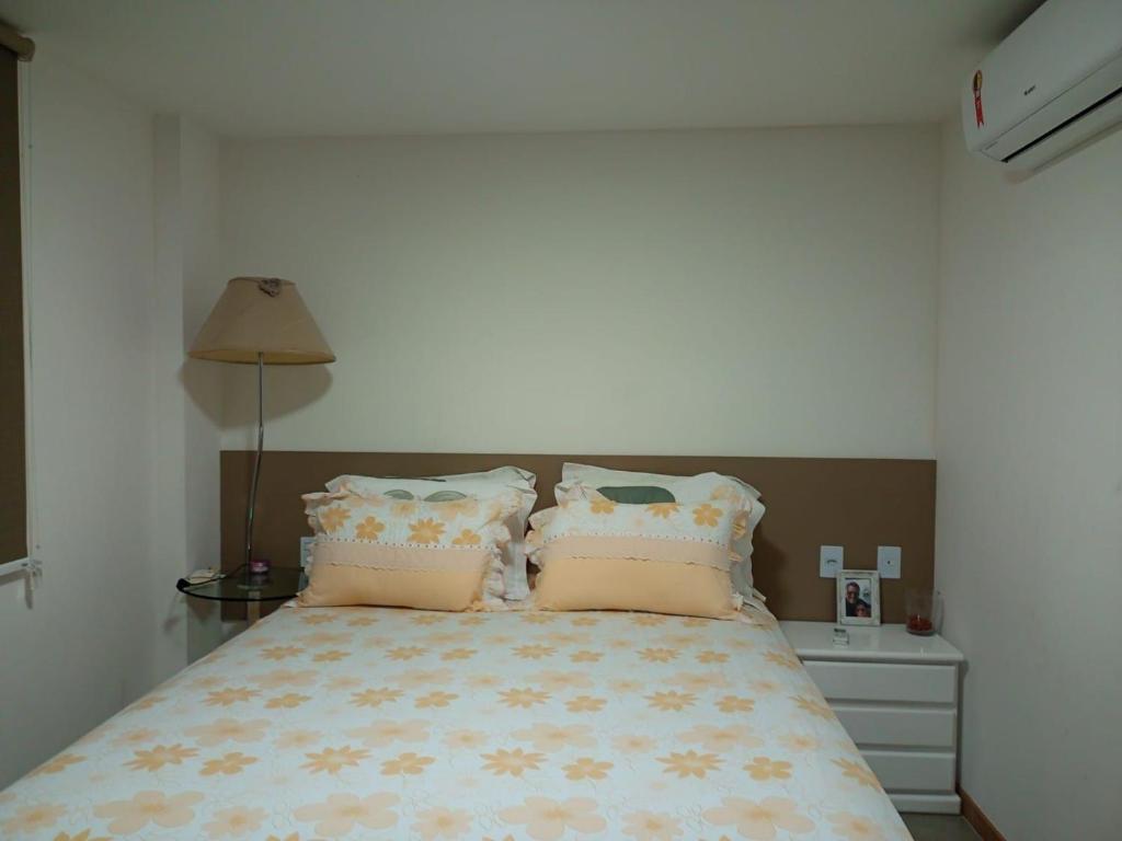 1 dormitorio con 1 cama con almohadas y lámpara en Ondas de Itacimirim, o paraíso é aqui! Pé na areia, en Itacimirim