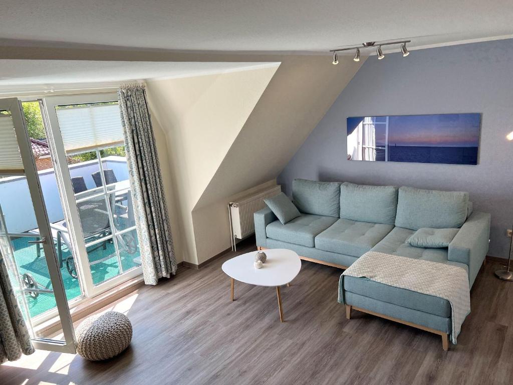 ein Wohnzimmer mit einem blauen Sofa und einem Tisch in der Unterkunft Haus Theo Luise Whg 03 in Sankt Peter-Ording