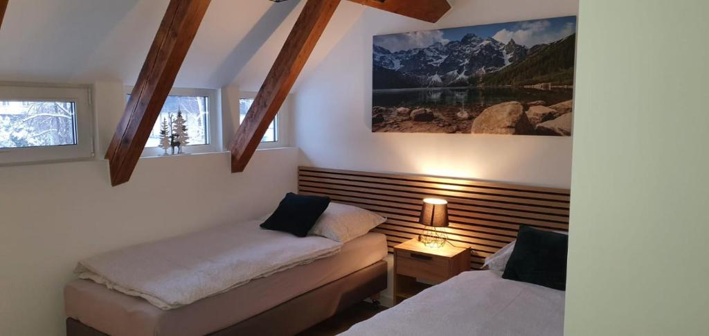 a bedroom with two beds and a picture on the wall at Pokoj 3 osobowy u Makosi in Bystrzyca Kłodzka