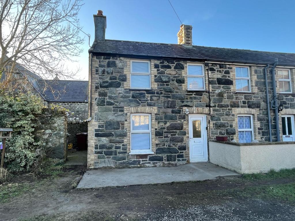 ein altes Steinhaus mit weißer Tür in der Unterkunft 1 Dinas cottages in Caernarfon