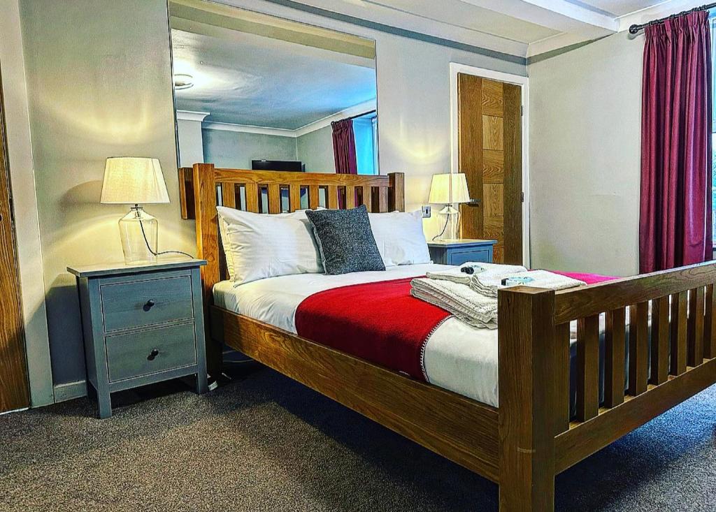 a bedroom with a wooden bed with two night stands and two lamps at The Hinds Head Hotel in Chorley