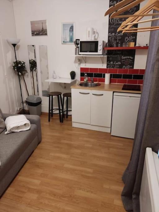 un salon avec un canapé et une cuisine dans l'établissement Studio Glacière, à Paris