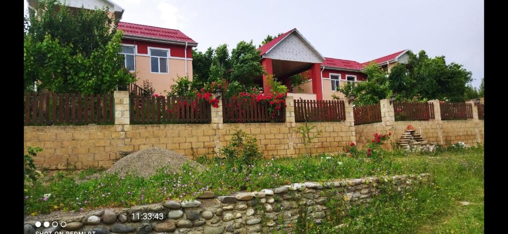 uma cerca de tijolos em frente a uma casa em Quba Guest House 