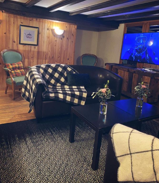a living room with a couch and a tv at Hôtel Restaurant "La Petite Auberge" in Bourg-Saint-Maurice