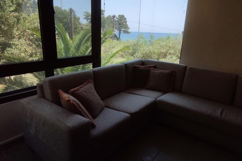 un divano in soggiorno con una grande finestra di K. Villa - Golden Beach a Chrisi Ammoudia