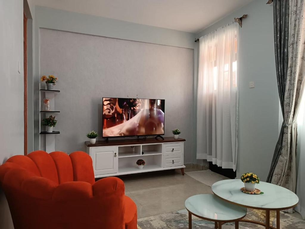 un salon avec une télévision à écran plat sur une armoire blanche dans l'établissement Epic homes, Secure1 bedroom furnished partment, ample Parking and WiFi available, à Nyeri