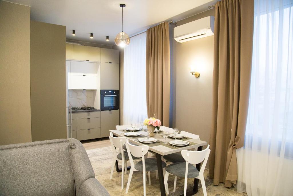 a dining room with a table and chairs and a kitchen at Apartment in center of Chisinau in Chişinău