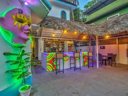 a bar with colorful stools and a bar with a drink at Candolim Boutique House in Candolim