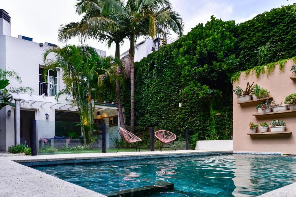 a swimming pool with two chairs next to a building at Casa Caravan - Plant Based Concept House in Buenos Aires