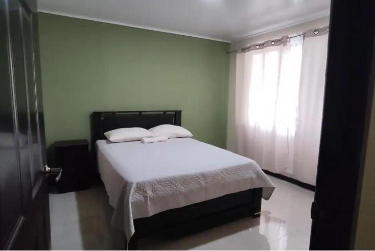 a bedroom with a bed with white sheets and a window at The Amigos House-Atelier in Parrita