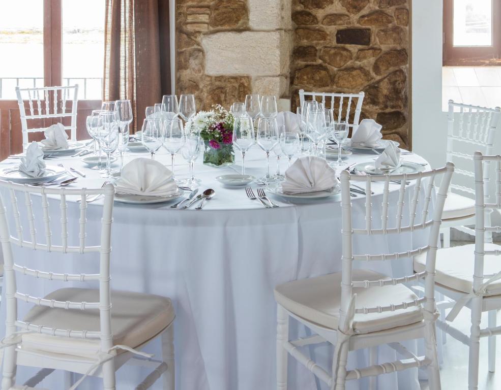 a white table with white chairs and plates and wine glasses at Hotel Tugasa Convento San Francisco in Vejer de la Frontera