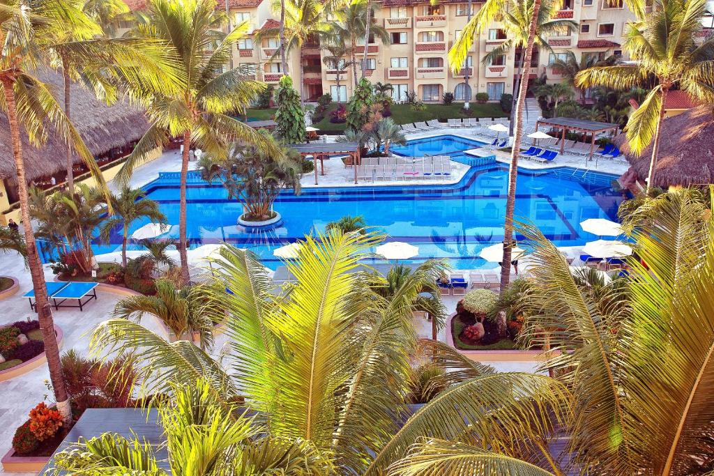 an aerial view of a resort swimming pool with palm trees at Canto del Sol Puerto Vallarta All Inclusive in Puerto Vallarta