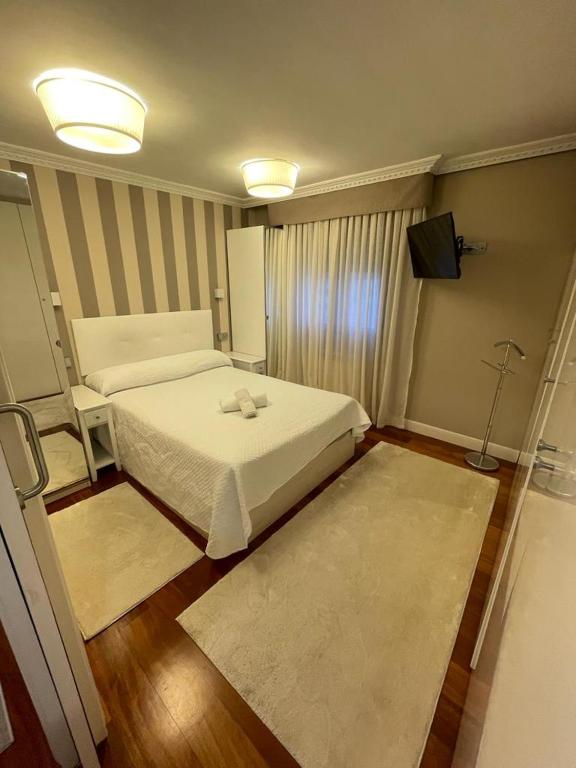 Apartamento RONDA CASTRO CENTRO con PARKING في كاسترو أورديالس: غرفة نوم بسرير ابيض وتلفزيون