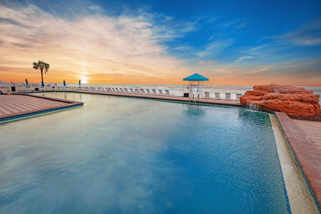 a swimming pool next to a beach with the ocean at Amazing Ocean View Studio Daytona Beach in Daytona Beach