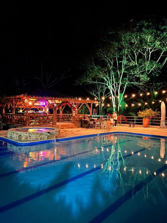 a swimming pool at night with a restaurant in the background at Hotel Parador del Gitano in Doradal