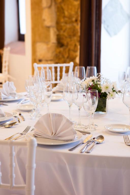 a white table with glasses and plates and silverware at Hotel Tugasa Convento San Francisco in Vejer de la Frontera