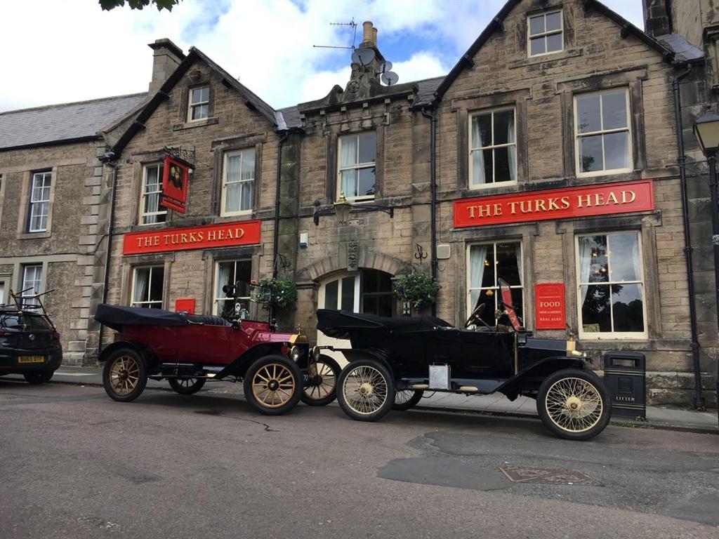 dos coches viejos estacionados frente a un edificio en Turks Head Rothbury, en Rothbury