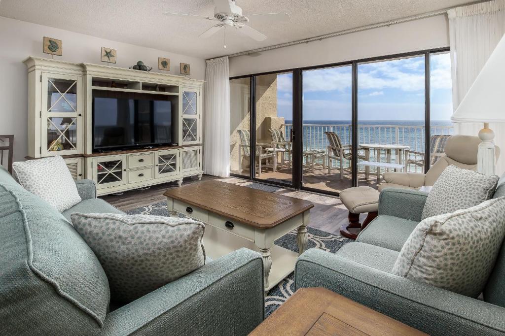 sala de estar con TV, sofá y sillas en Gulfside 503 by Brooks and Shorey Resorts condo, en Fort Walton Beach
