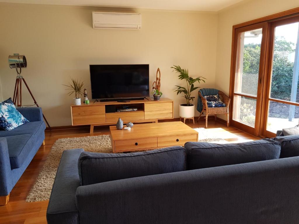 a living room with a couch and a flat screen tv at Sandy Bottoms in Point Lonsdale