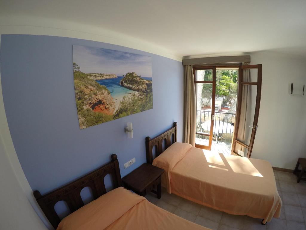 1 dormitorio con 2 camas y ventana en Hostal Playa en Cala Santanyi